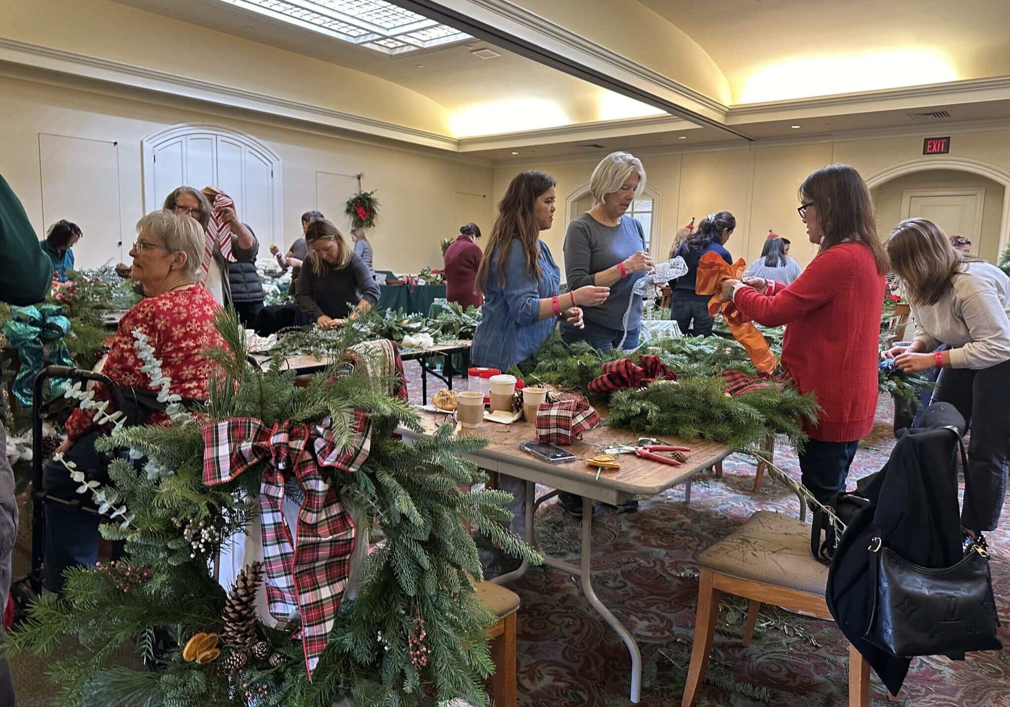 2023 Holiday Flora Party in the Visitors Center. Participants decorate wreaths with evergreens and holiday décor.