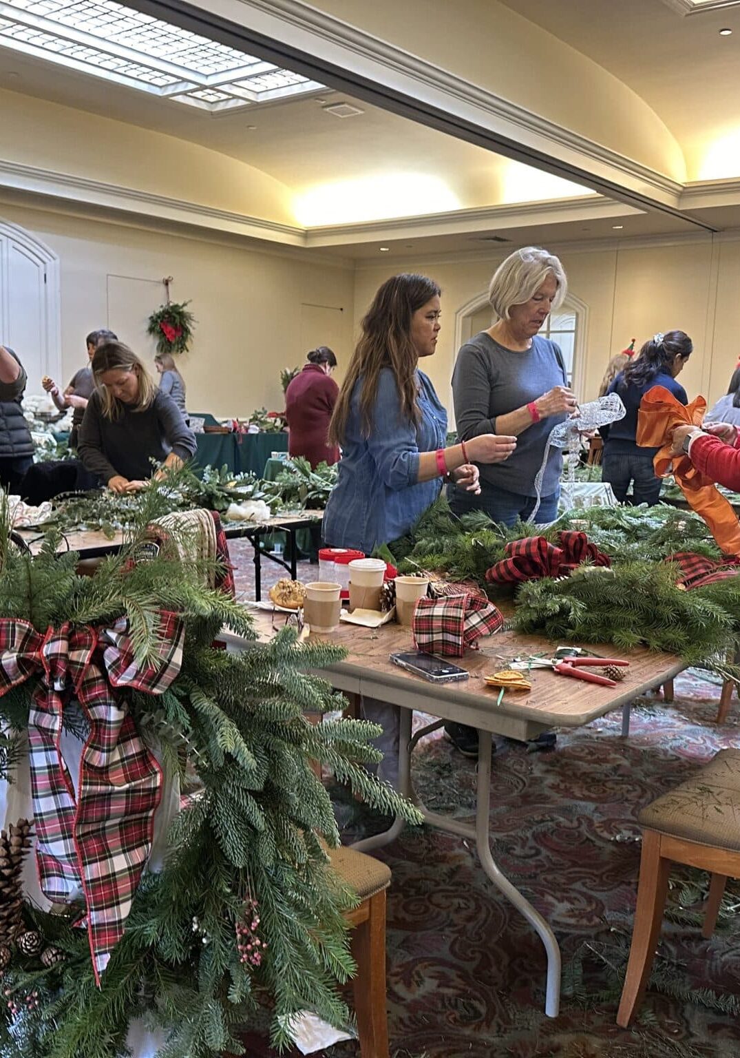 2023 Holiday Flora Party in the Visitors Center. Participants decorate wreaths with evergreens and holiday décor.